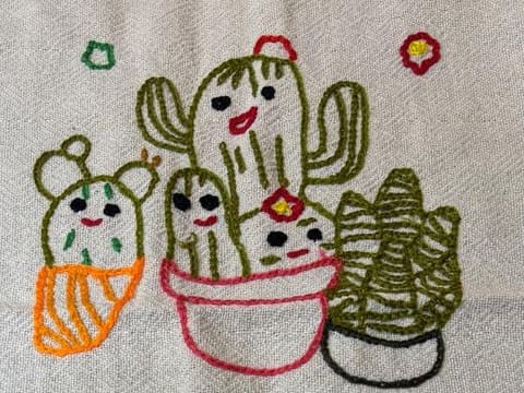 Quatro cactos de vaso bordados, cada um com sua carinha, e florzinhas vermelhas.