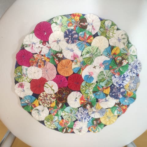 Dezenas de flores de fuxico, de retalhos estampados e coloridos, costuradas lado a lado.